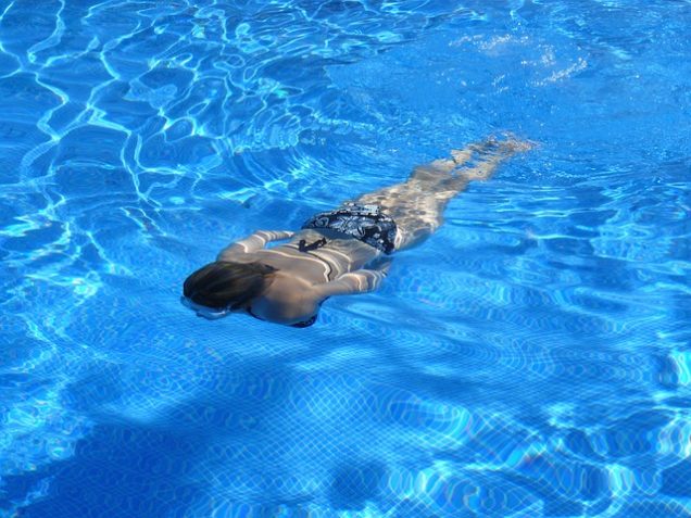 A person swimming in a pool at The Montecristo Apartments in Stone Oak, San Antonio.